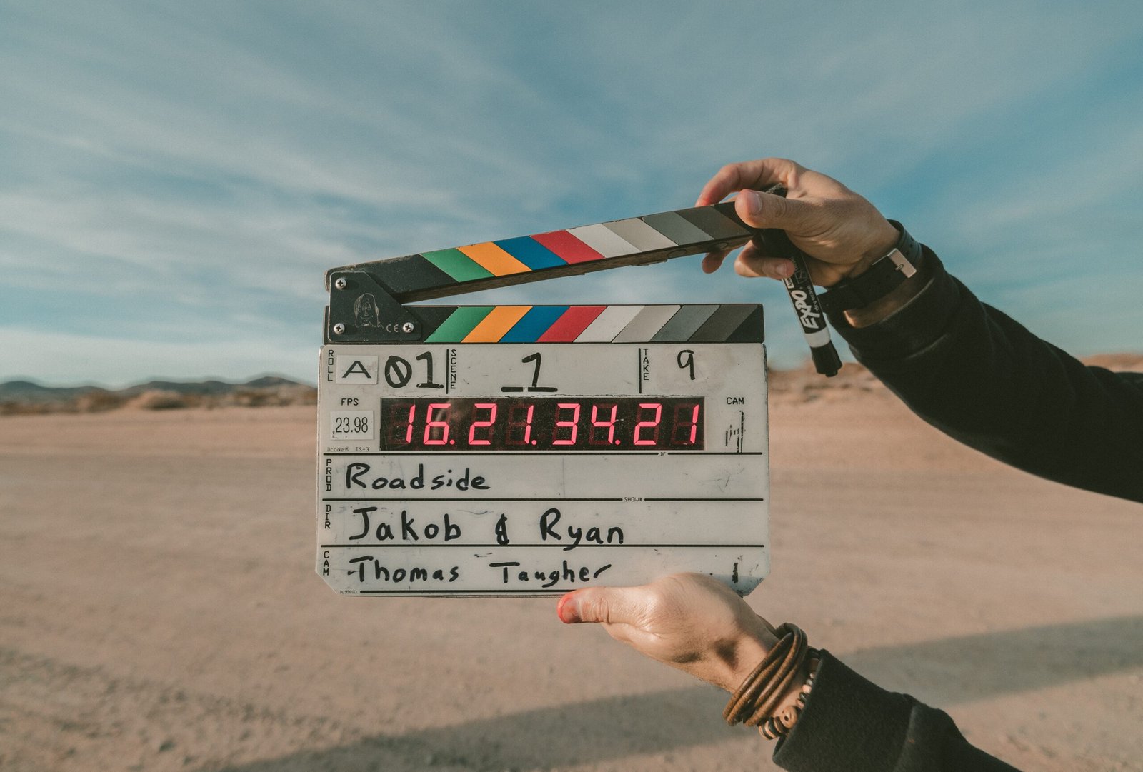Hand holding a film clapperboard on a beach